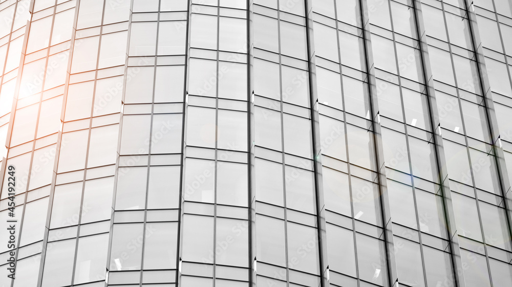 Fototapeta premium Modern architectural details. Modern glass facade with a geometric pattern. Contemporary corporate business architecture. Red sun on horizon. Black and white toned image.
