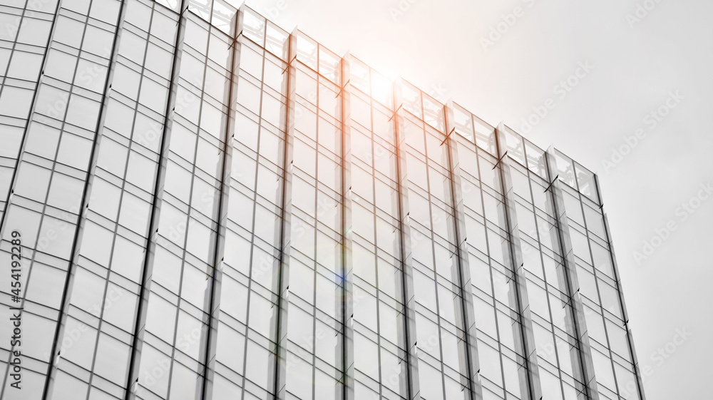 Fototapeta premium Modern architectural details. Modern glass facade with a geometric pattern. Contemporary corporate business architecture. Red sun on horizon. Black and white toned image.