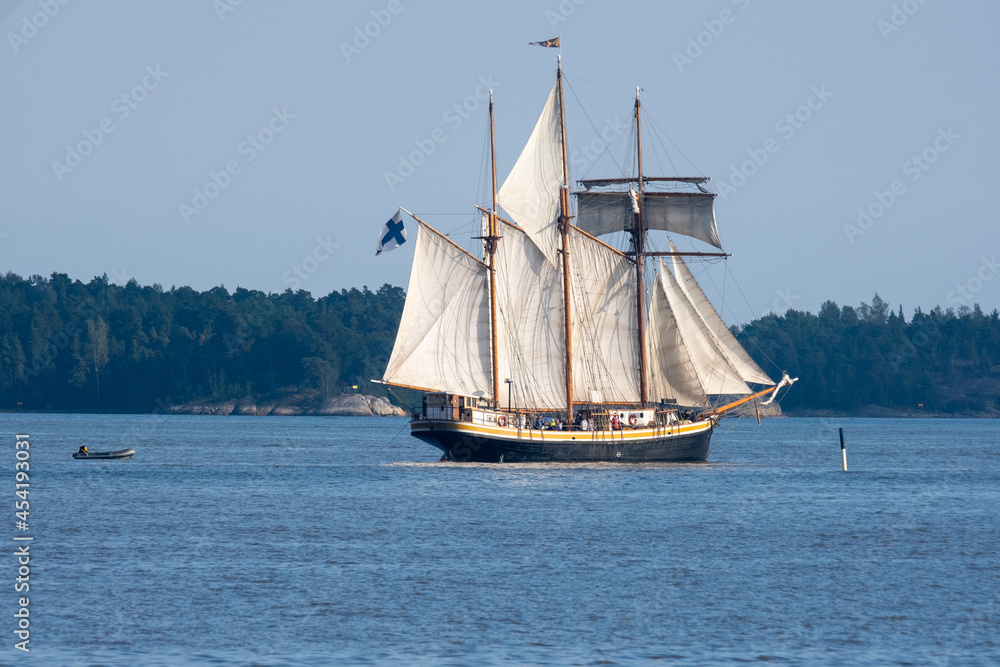 Fototapeta premium An old schooner with rised sails sailing across the horizon.