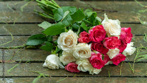 Bouquet of roses  white and pink  thrown over the wooden bridge to the lake on a rainy day 