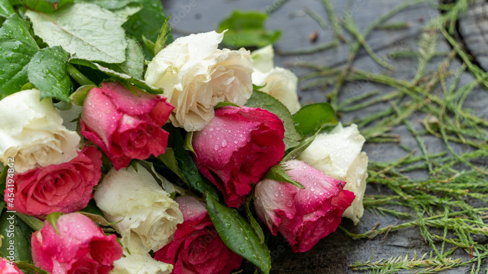 Fototapeta premium Bouquet of roses, white and pink, placed on a large tree stump near the lake, on a rainy day, close up