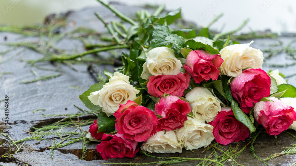 Bouquet of roses, white and pink, placed on a large tree stump near the lake, on a rainy day, close up Bouquet of roses, white and pink, placed on a large tree stump near the lake, on a rainy day, close up