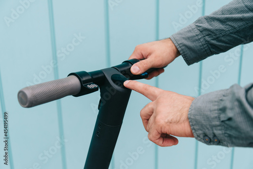 Close-up on the hands of a young man. Man turns on the electric scooter to go.
