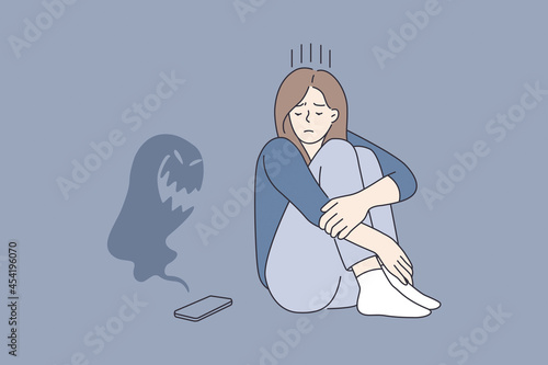 Cyberbullying and abuse in internet concept. Young sad depressed girl cartoon character sitting looking on smartphone with monster flying over it vector illustration 