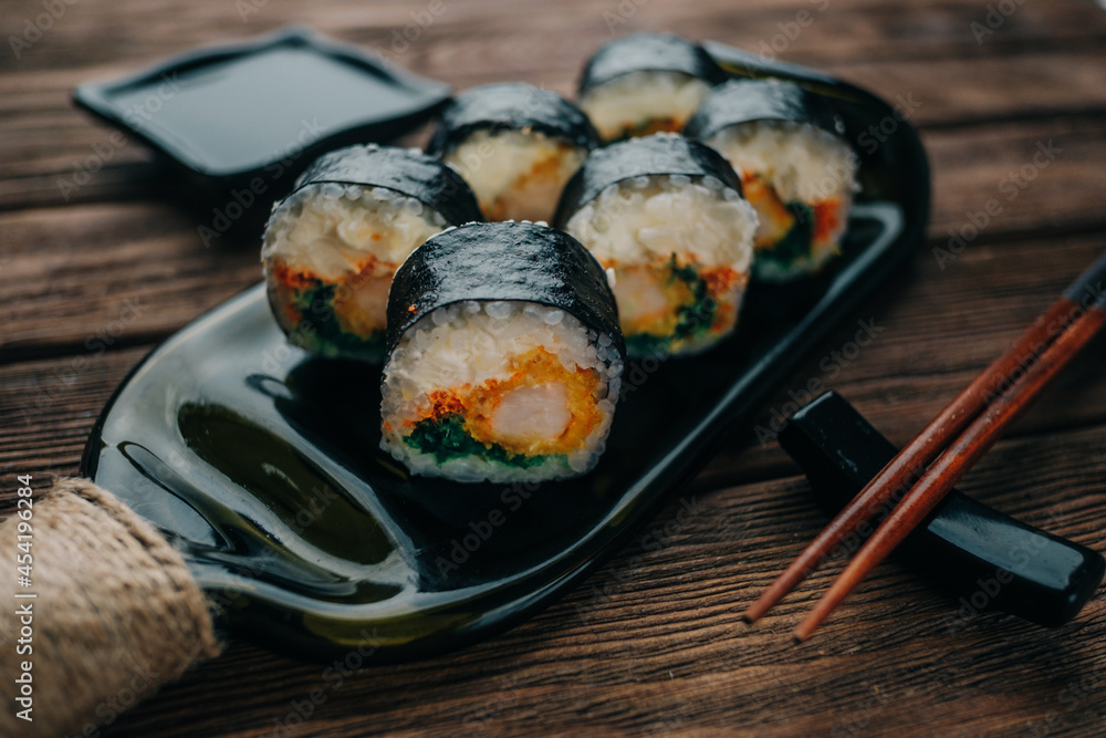 Set of sushi rolls lies on a plate made from a wine bottle. Chopsticks and soy sauce lie nearby. Set of sushi rolls lies on a plate made from a wine bottle. Chopsticks and soy sauce lie nearby.