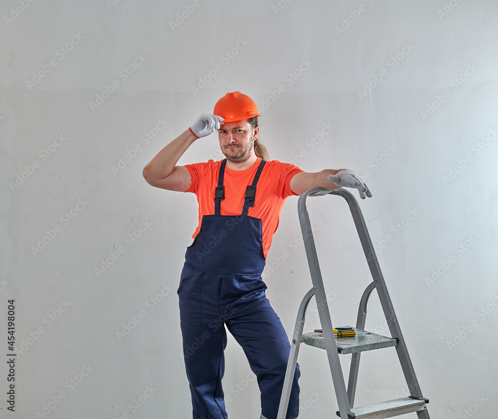 in gloves, the foreman leaned on a metal step-ladder in gloves, the foreman leaned on a metal step-ladder