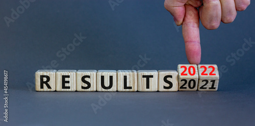 2022 results new year symbol. Businessman turns a wooden cube and changes words 'results 2021' to 'results 2022'. Beautiful grey background, copy space. Business, 2022 results new year concept.