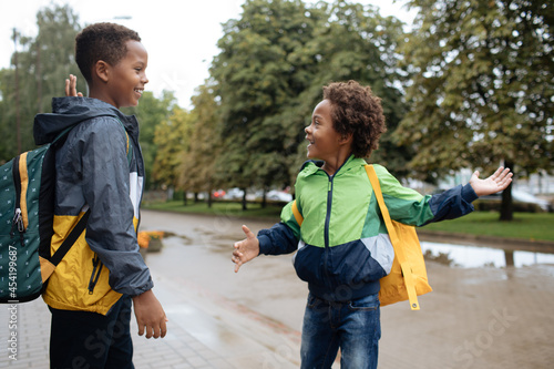 Little boys high five. Two African American boys next to the school. Back to the school concept. Kids standing outside and happy to meet each others. Happy black children. First day of school