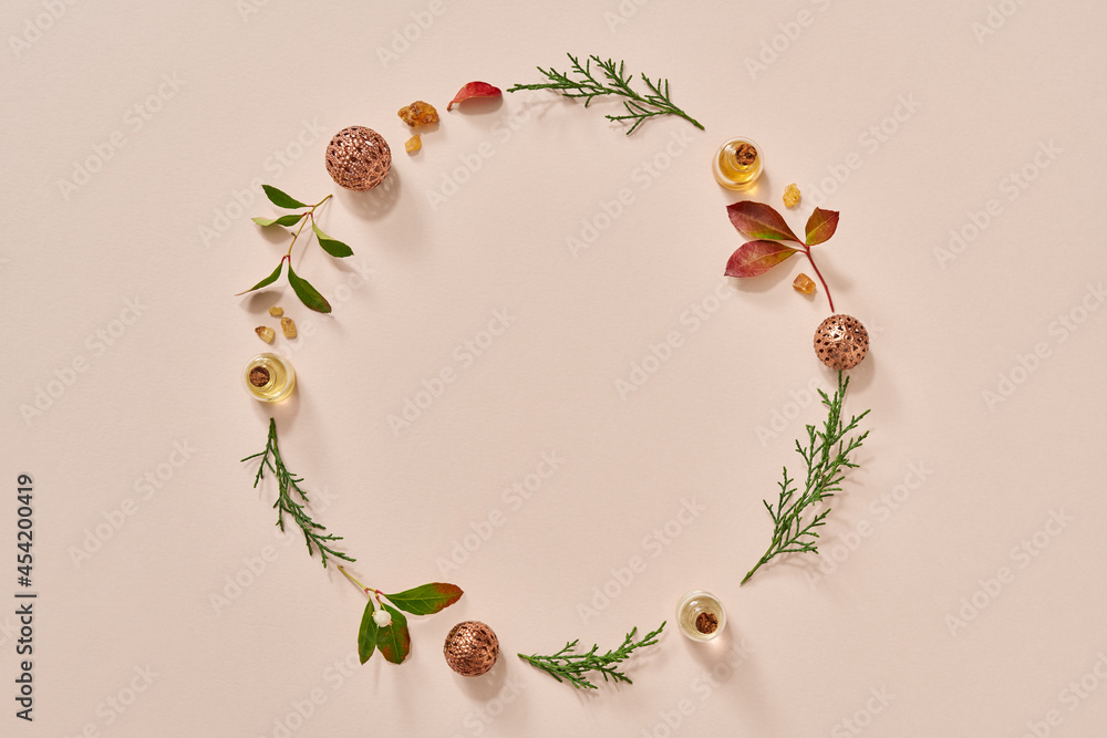 Christmas circular background with essential oil bottles, frankincense, wintergreen and thuja, with copy space