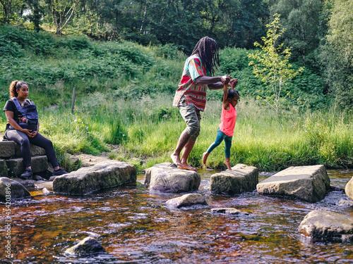 UK, Father and daughter walking on rocks shallow creek