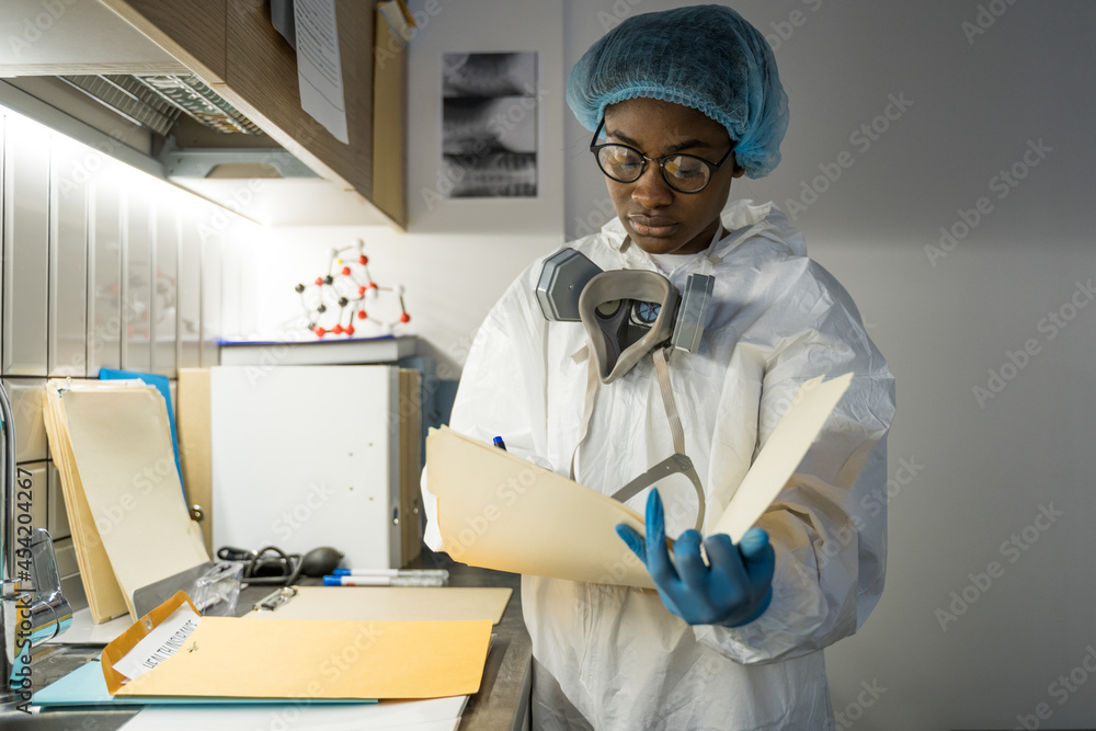 Fototapeta premium Doctor reading documents after hard day with at the isolation unit