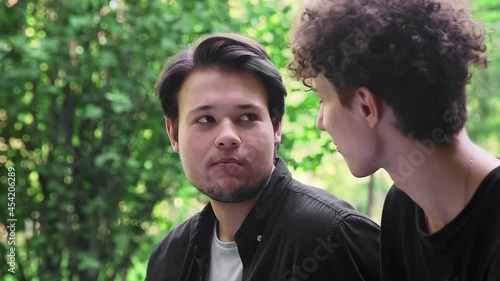 A guy feeds grapes to another guy in the park in the summer