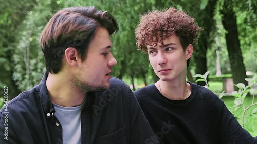 A guy puts his head on the shoulder of another guy in the summer in nature