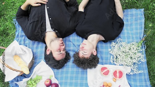 Two guys in love in the summer lie on a blanket in nature and communicate top view
