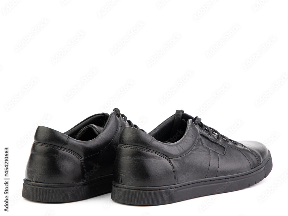 Black leather classic sneakers with laces. Casual women's style. Black rubber soles. Isolated close-up on white background. Back side view. Fashion shoes.