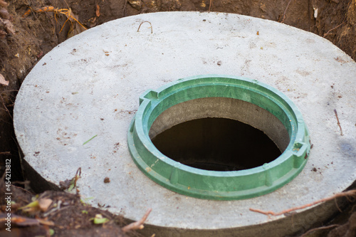 Construction of a septic tank. Large concrete rings embedded in the ground, from above an open sewer hatch, unprotected by a cover from falling.