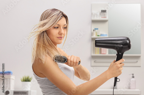 Young woman using a hairbrush and a blowdrying hair