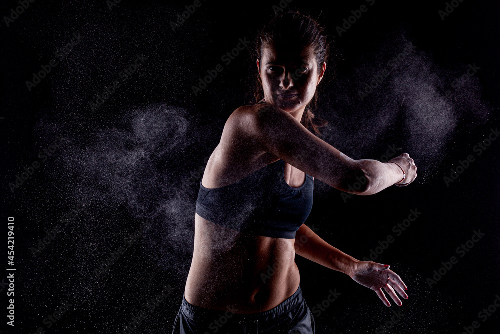 Kickboxer kirl with magnesium powder on her hands, punching with dust visible.