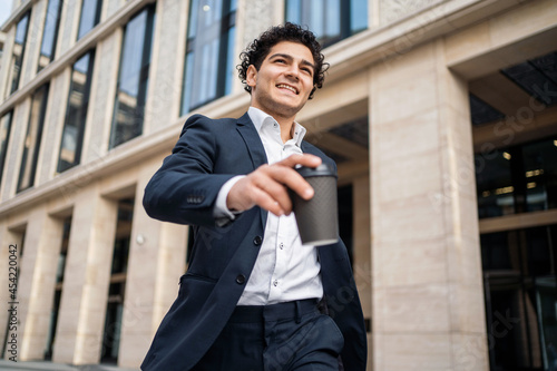 Wallpaper Mural A young businessman holds a cup of coffee in his hand. A male entrepreneur goes to work. The financier is in a good mood and a modern business suit. Torontodigital.ca