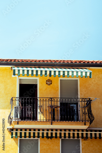 A small Italian yellow house with balcony by the sea, covered by a blue sunny sky