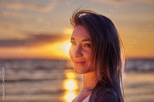Portrait of happy white woman on seaside during sunset. © grigvovan