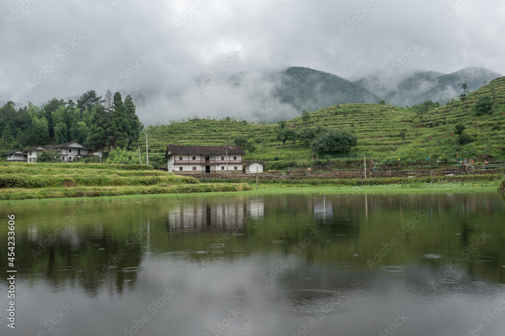 The lake reflected the mountain with houses and fog on the mountain