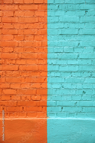 Brick wall  divided in half and painted with orange and turquoise paint