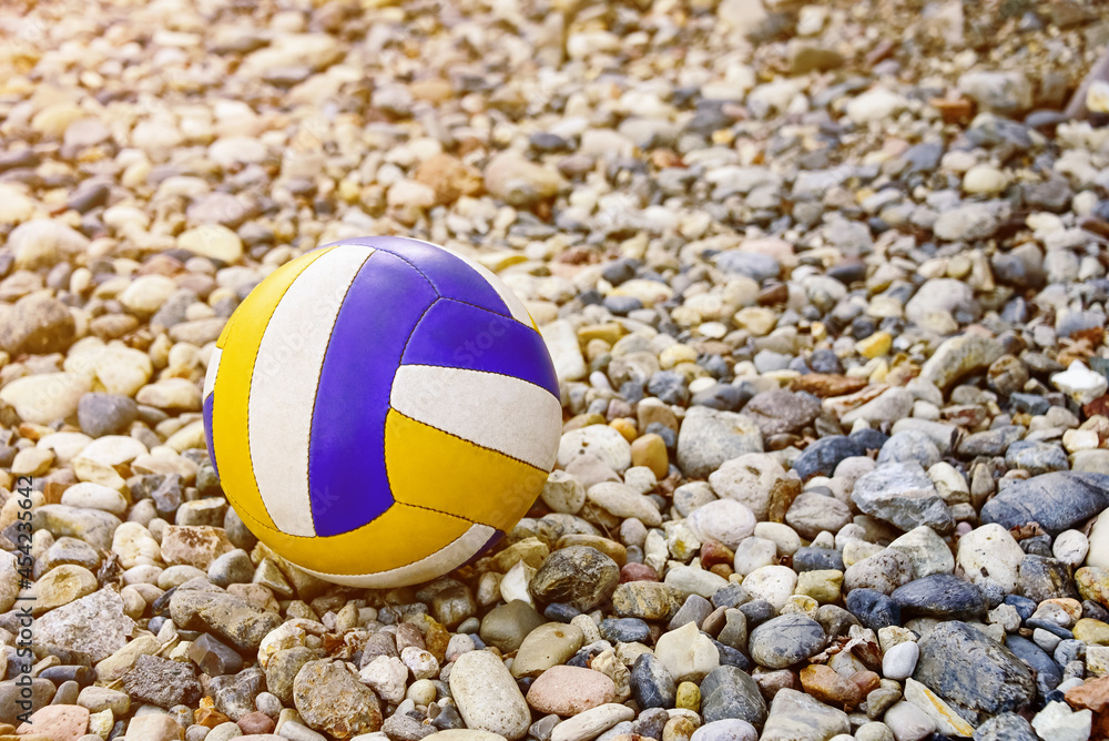 Close up of colored volleyball ball on a sea pebble beach. Summer beach games