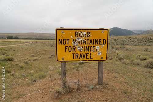 Road not maintained for winter travel sign, with bullet holes