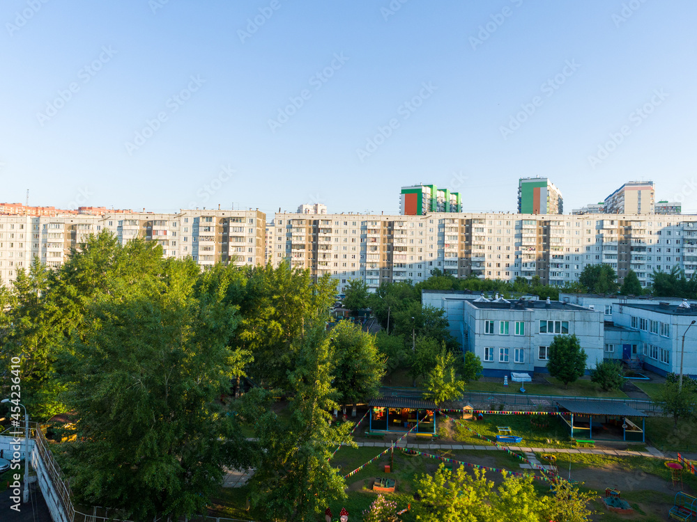 Summer evening in a residential area of a Russian city. Panel nine-story buildings against the background of a clear sky
