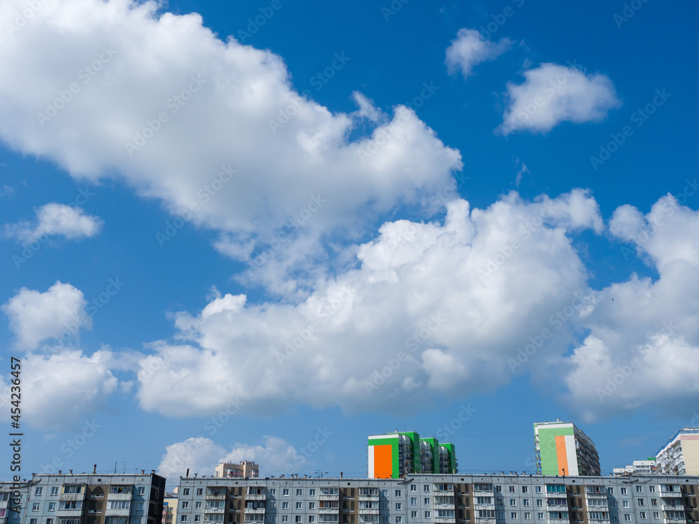 Beautiful white clouds in the blue sky over residential buildings. Sleeping urban area. Summer day