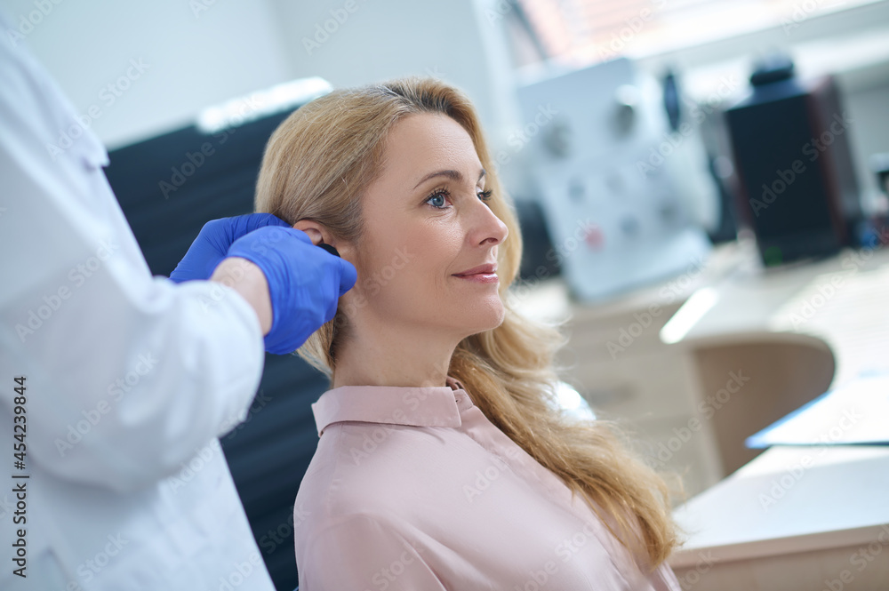 Pleased patient undergoing a medical checkup at a hearing clinic Pleased patient undergoing a medical checkup at a hearing clinic