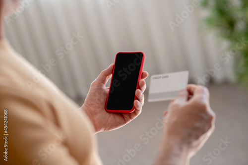A man holding a smartphone and a credit card in hand