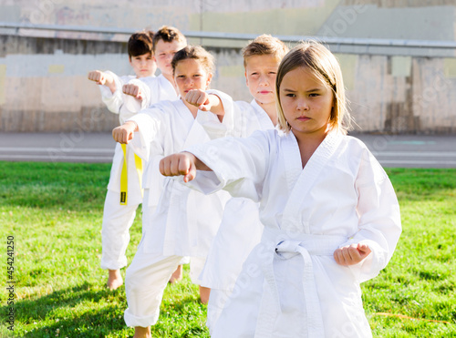 Group of children training a new moves during karate class at summer outdoors