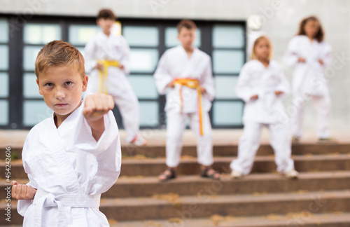Focused european preteen boy practicing karate on sunny day at schoolyard