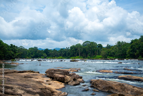 River Flows Between Rocks In Rain forest under blue cloudy sky Chalakudy Kerala