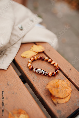 Tibetan talisman bracelet with minerals and magic dzi bead to attract good luck in life. energy trappings. autumn still life bracelet in leaves on wood. selective focus