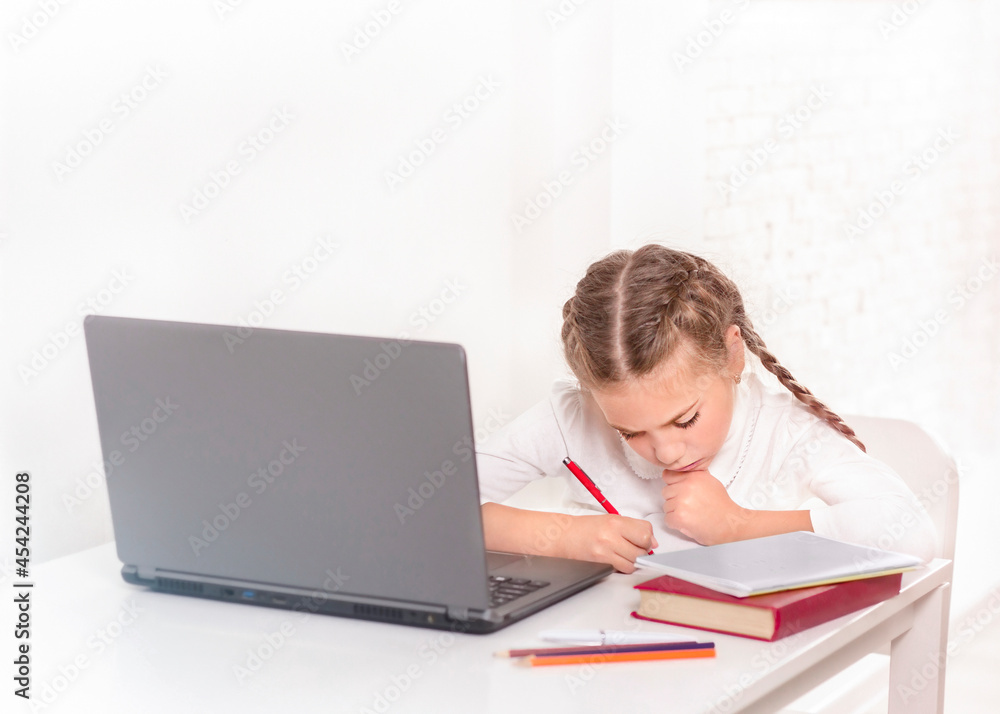 Schoolgirl studying at the table with laptop Schoolgirl studying at the table with laptop