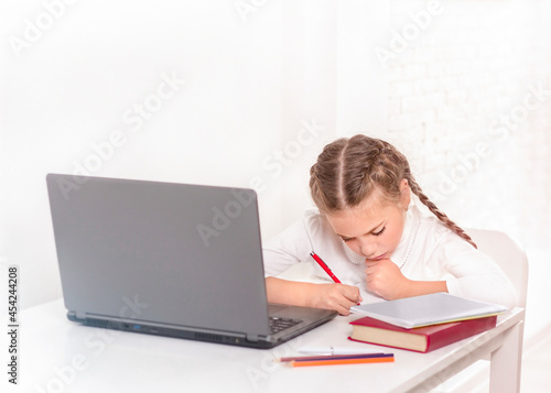 Schoolgirl studying at the table with laptop