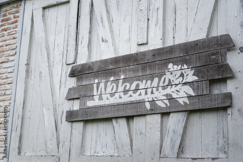 Welcome text sign antique wooden board which is installed on the wall. Sign and symbol object photo in monotone. 