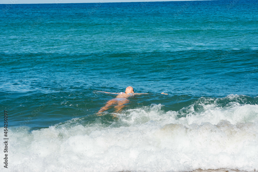 gorgeous young woman in bikini bathing in the ocean