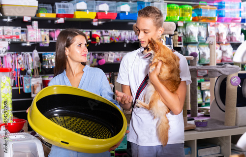 Young woman and boy customers choosing plastic toilet in pet store
