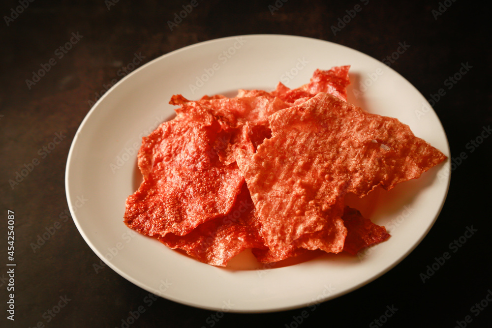 Sliced sheets of dried and crispy pork on white dish.