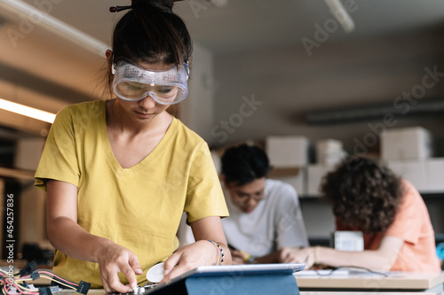 Asian Student Girl with protective goggles learning technology, robotics and electronics in High School