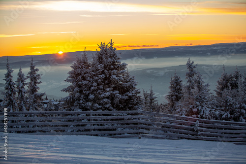 Kvitfjell Ski Resort landscape. Frozen snow-covered firs at orange sunset 