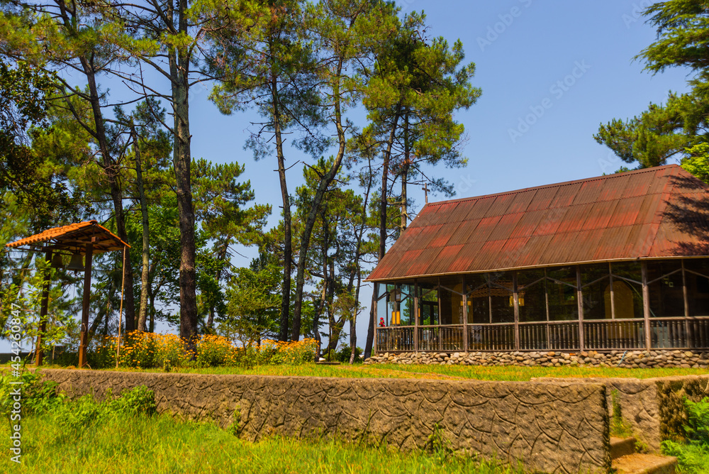 KOBULETI, GEORGIA: Wooden Orthodox church in a shady park on a sunny summer day. KOBULETI, GEORGIA: Wooden Orthodox church in a shady park on a sunny summer day.