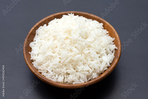 Dish of rice in wooden bowl on dark background.