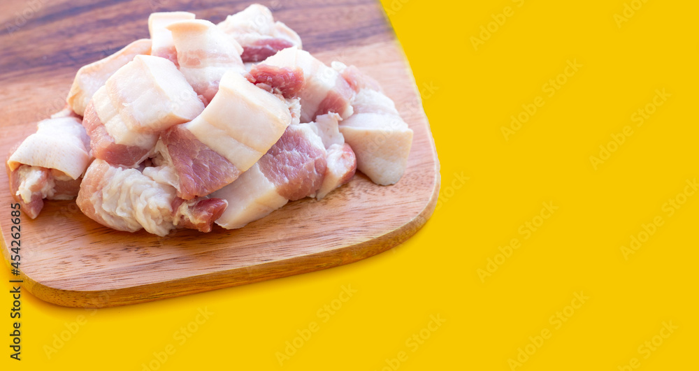 Streaky pork on cutting board on yellow background.