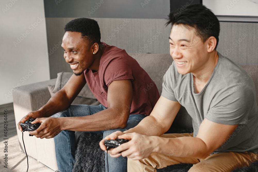 Fototapeta premium Two friends playing Playstation in the living room