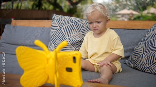 Toddler child watching a cartoon on a digital tabled in a kid -riendly yellow butterfly case photo